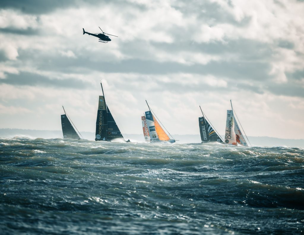 La flotte de la Route du Rhum 2022 au départ, survolée par un hélicoptère