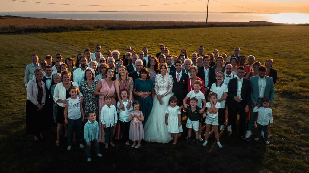 Vue drone de mariés et de leurs invités au coucher du soleil, la mer en arrière-plan