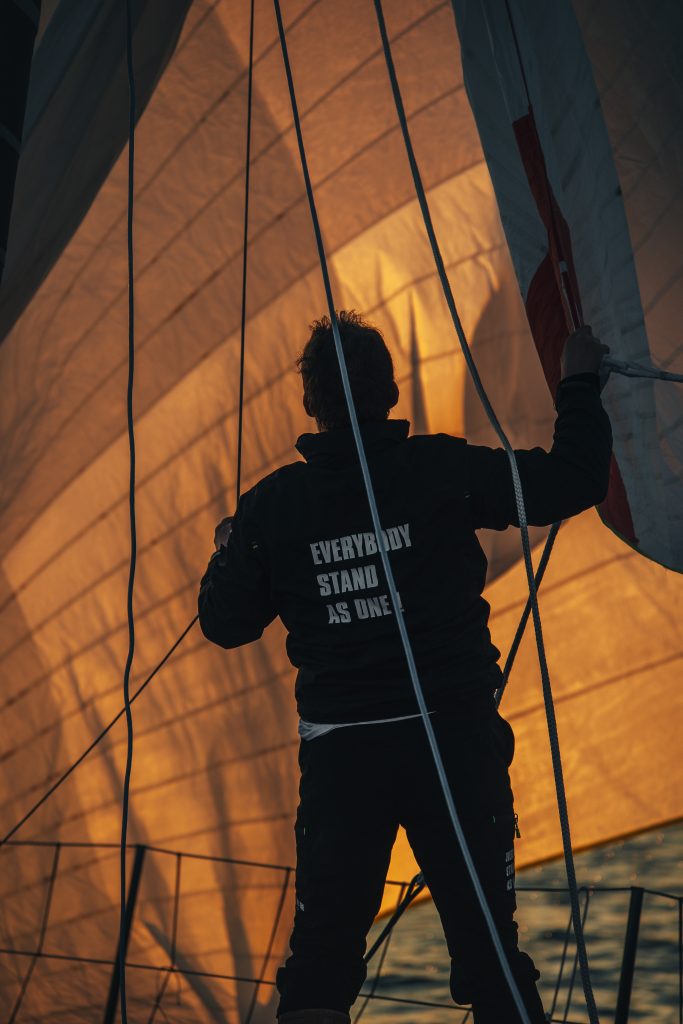 Le navigateur Éric Bellion en ombre chinoise devant sa voile au soleil