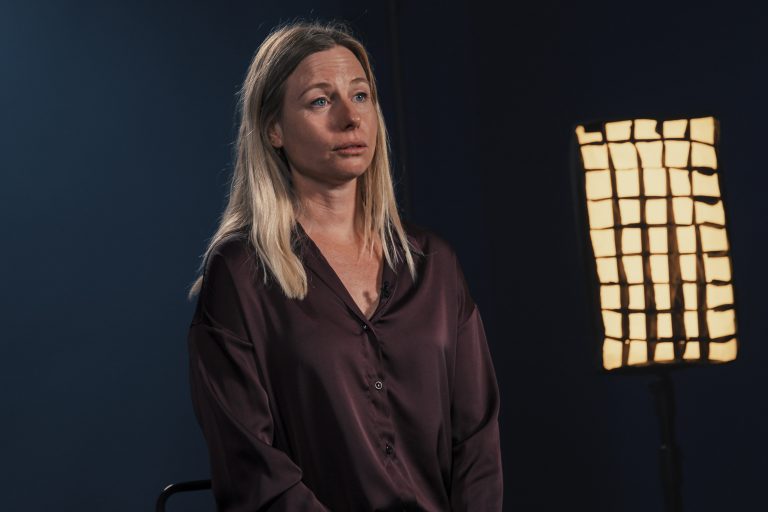 Interview film&eacute;e d&rsquo;une femme sur fond sombre, &eacute;clair&eacute;e par un projecteur de studio