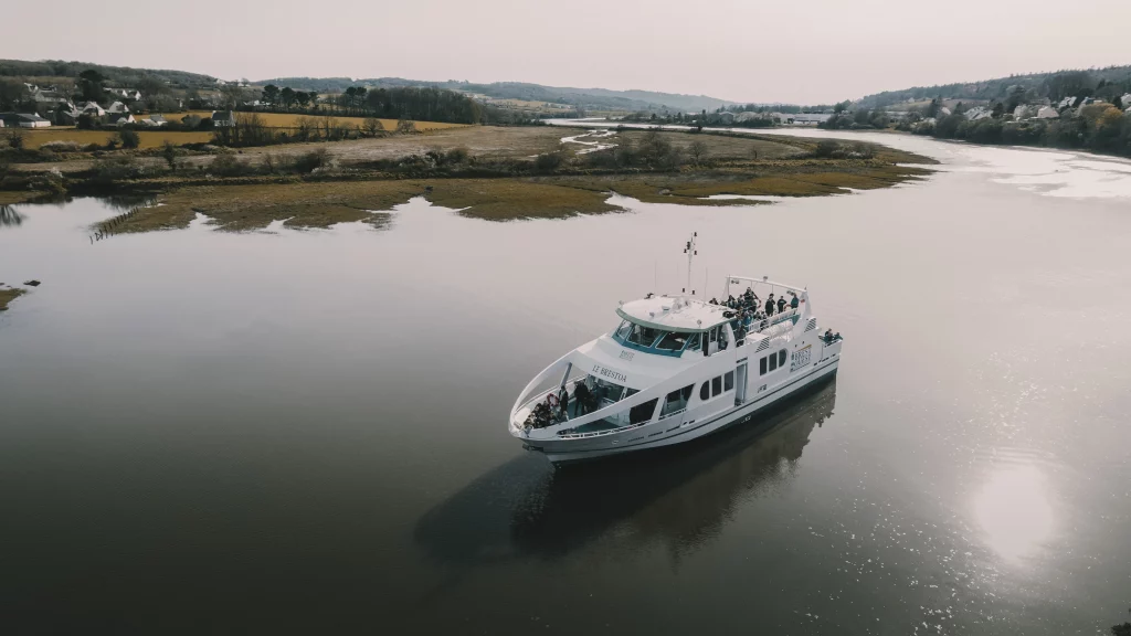 Vue a&eacute;rienne par drone stabilis&eacute; d&rsquo;un bateau de passagers naviguant sur une rivi&egrave;re