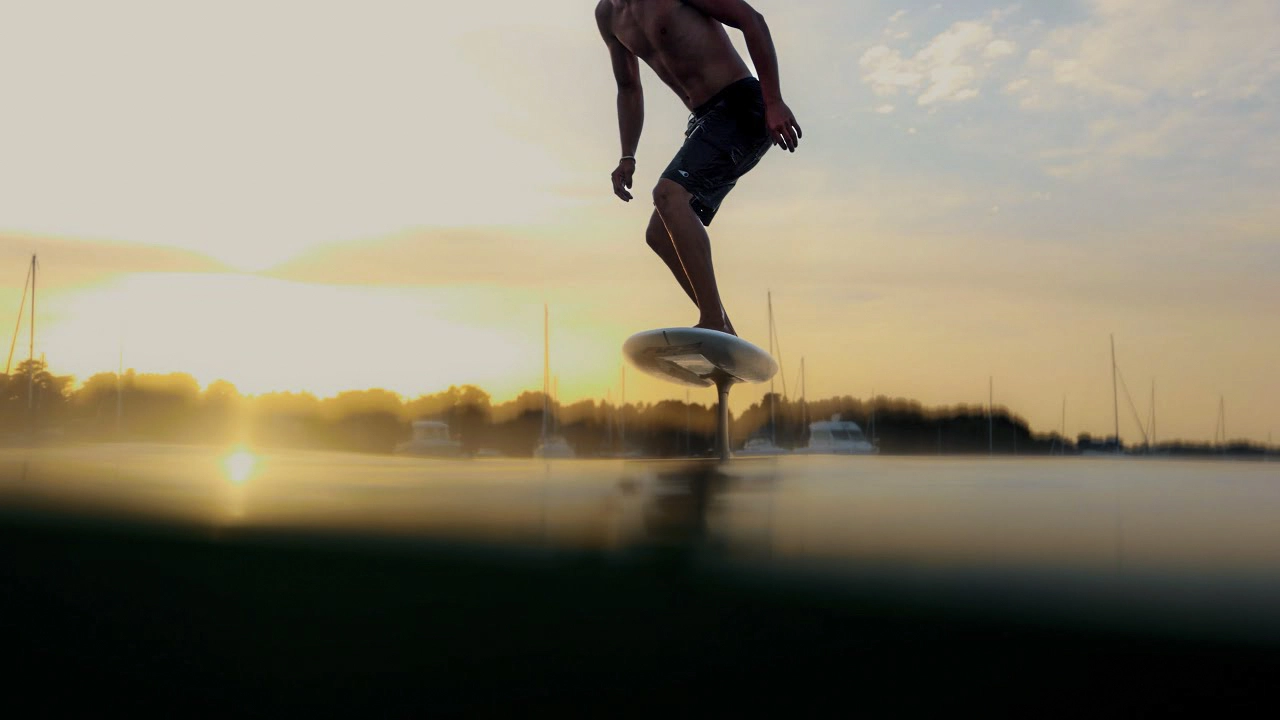 Rider portant une planche AFS Foil sur un spot en bord de mer